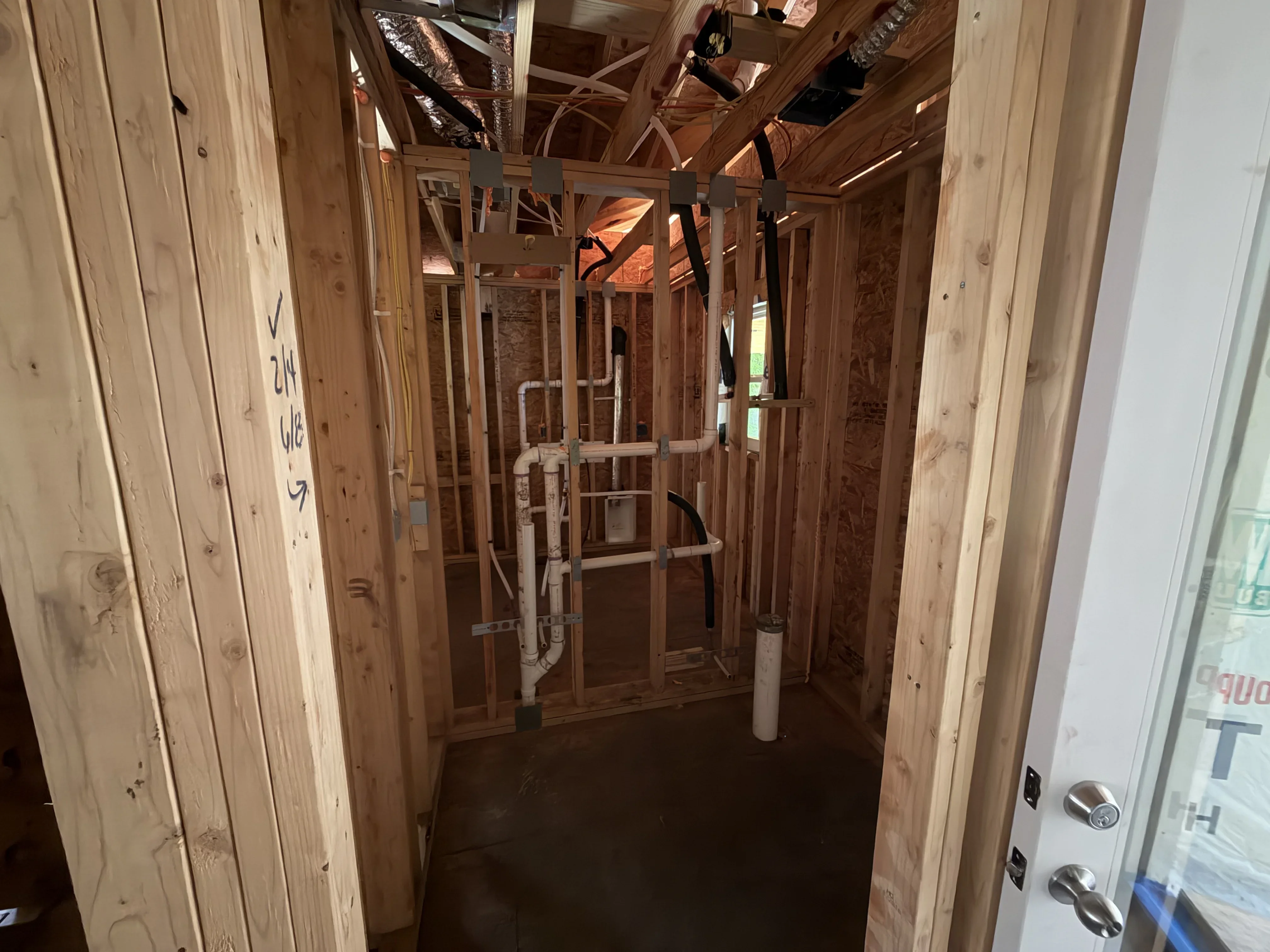 Interior framing with white PVC plumbing pipes and drain lines installed during construction rough-in phase