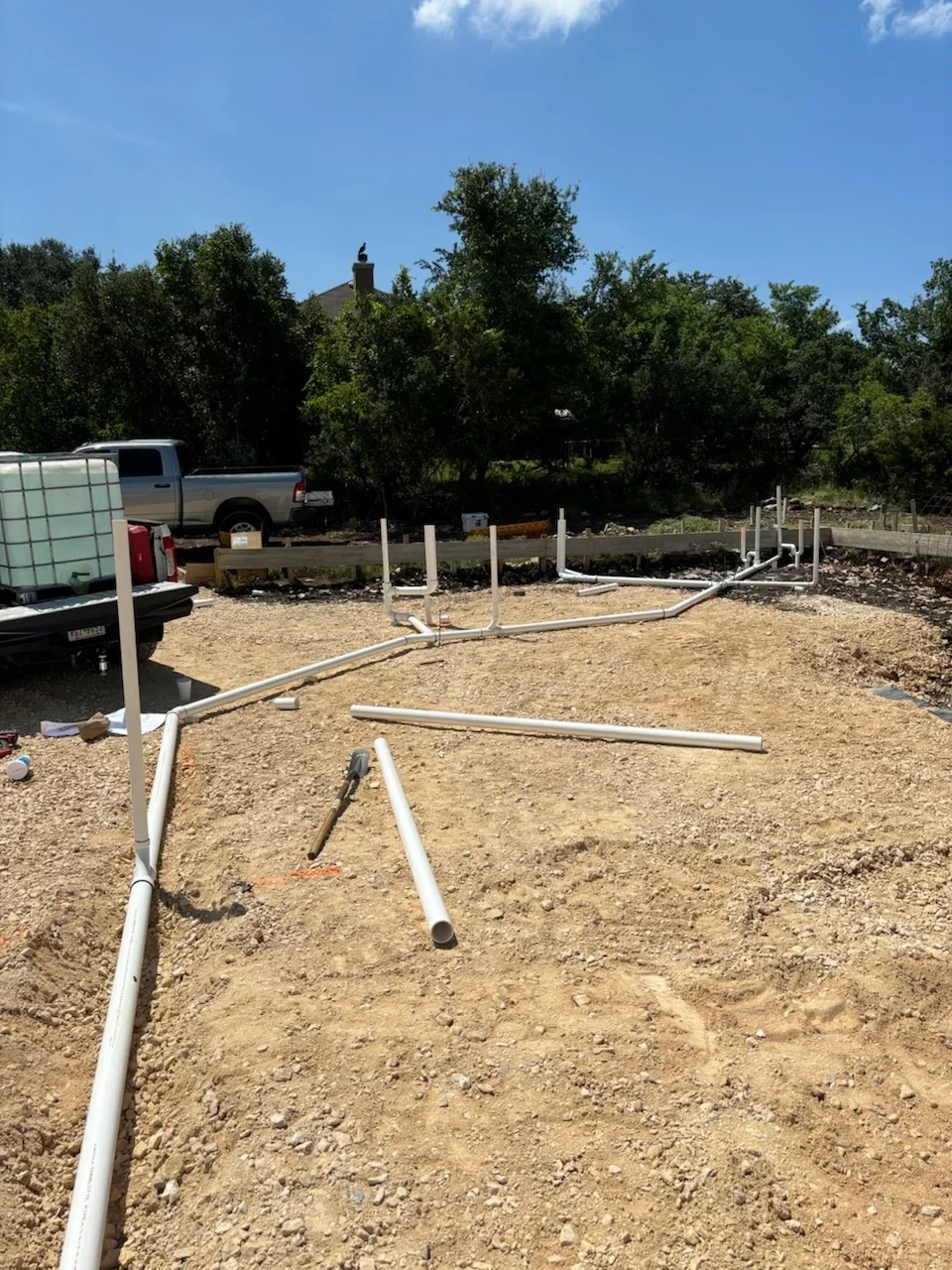 Septic system installation with white PVC pipes and concrete posts on gravel foundation