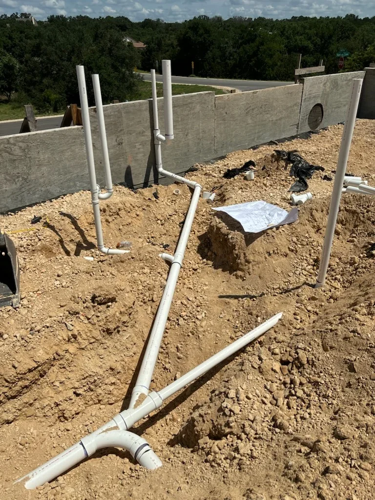 PVC plumbing pipes and risers installed in concrete foundation with utility vault walls